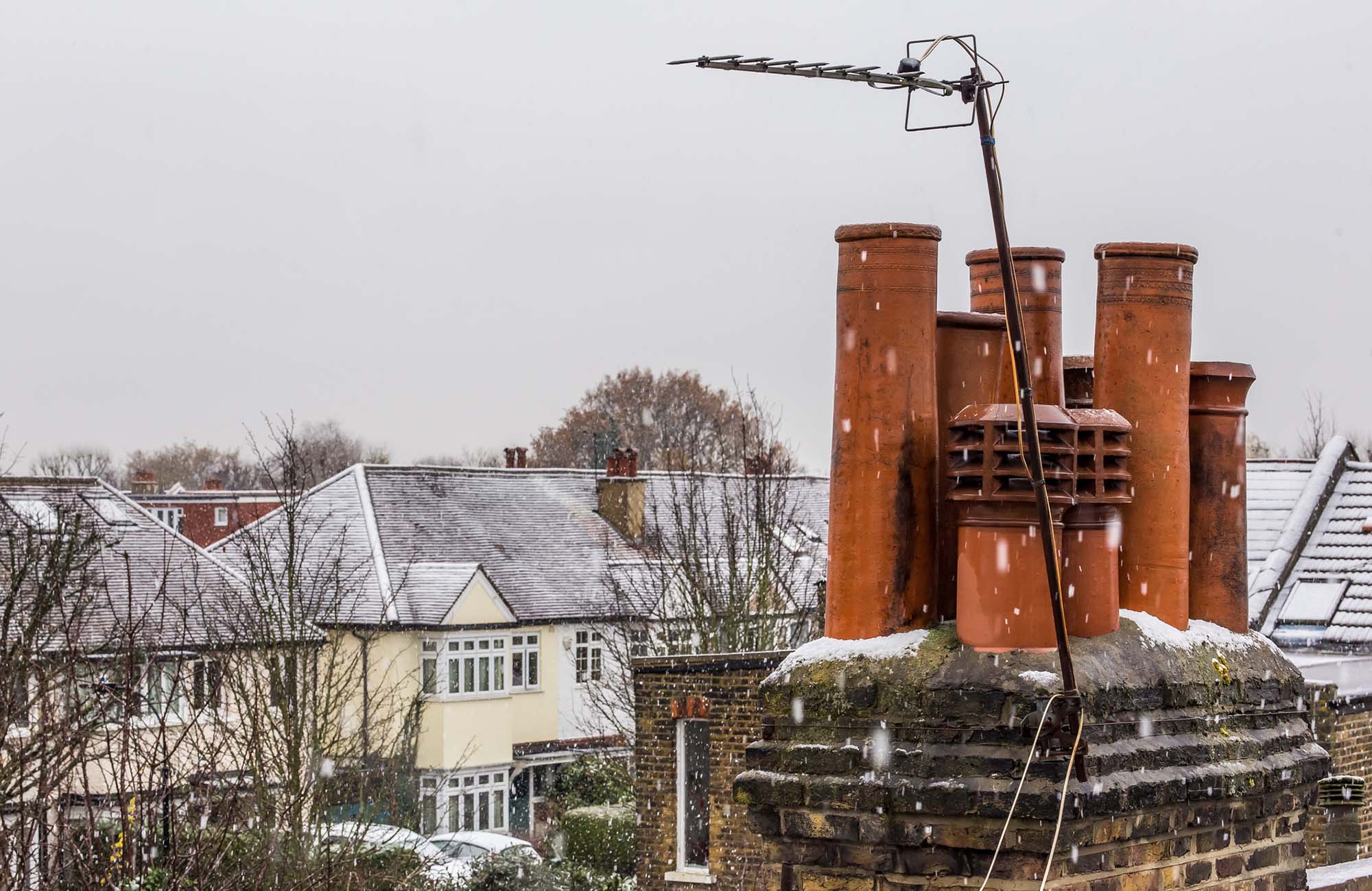 Suburb chimney stack on snowy winter day, UK