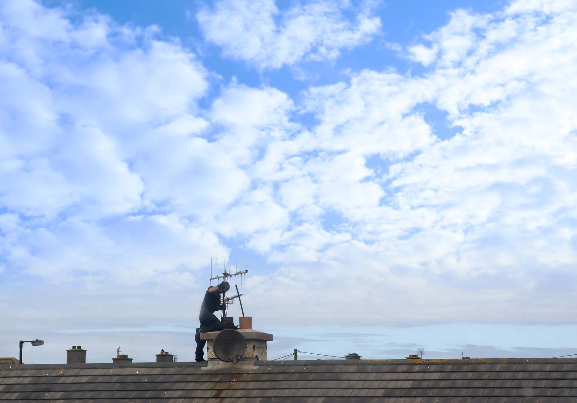 Chimney sweep at work on the rooftop of a housing estate